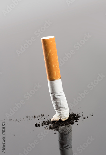 Cigarette butt with smoke on grey