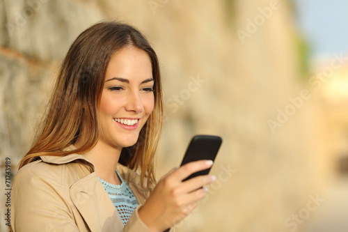 Happy woman using a smart phone in an old town