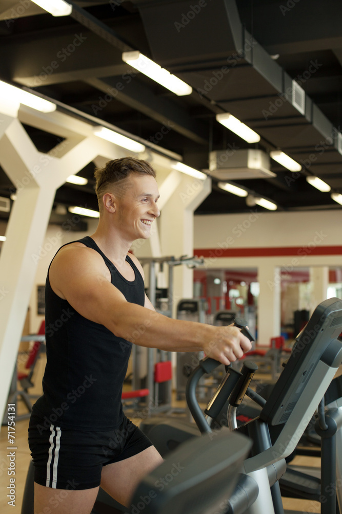 Merry young man exercising on treadmill Merry young man exercising on treadmill