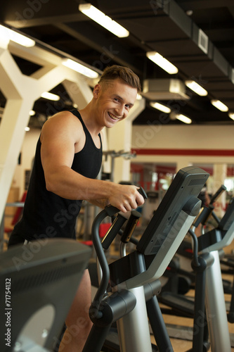 Cheerful runner posing at camera in gym