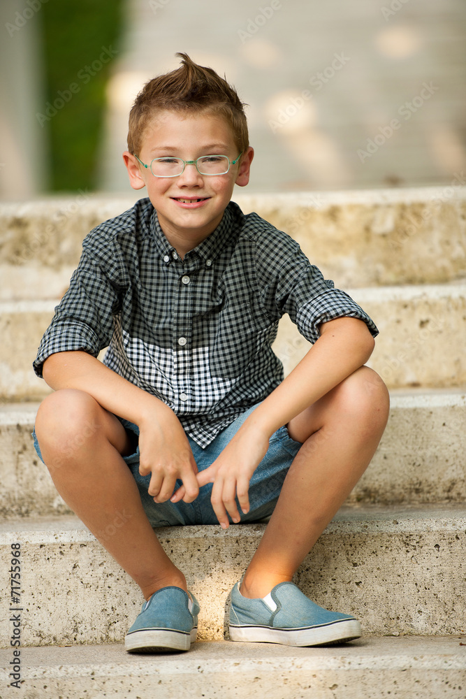 me young boy sitting on stairs in park