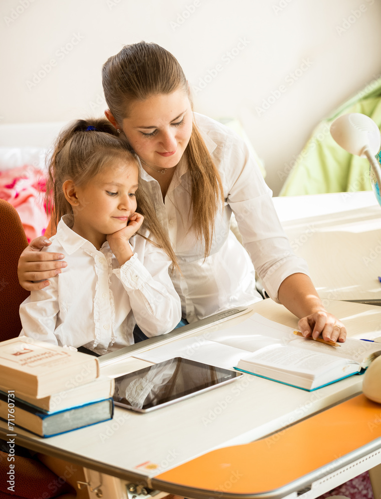 mother pointing in exercise book and explaining homework to daug mother pointing in exercise book and explaining homework to daug