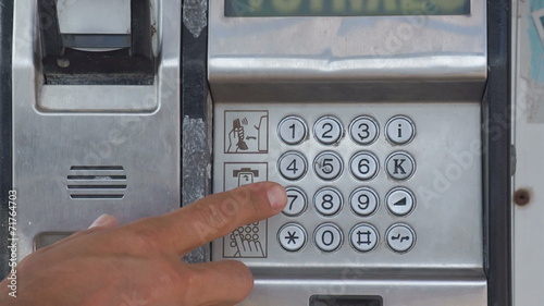 Close-up of a man's hand taking an outdoor payphone photo