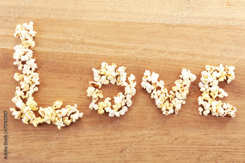 Love word formed with popcorn on wooden table
