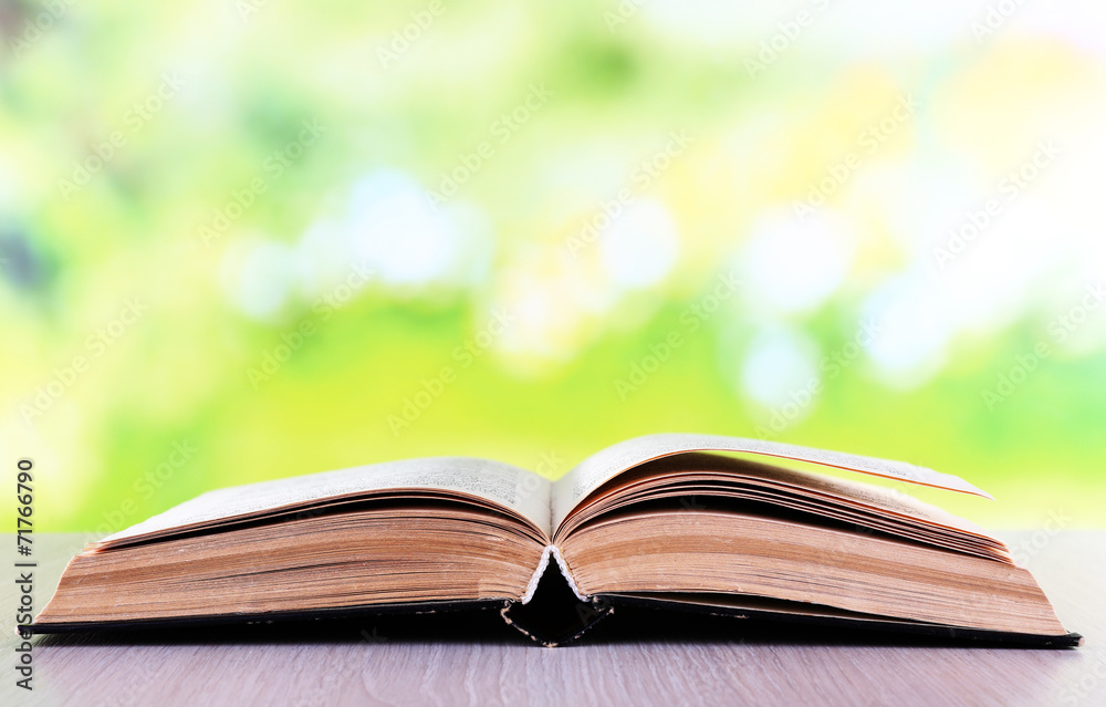 Open book on wooden table on natural background Open book on wooden table on natural background