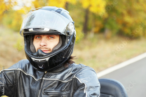 Biker man in black helmet sits on bike