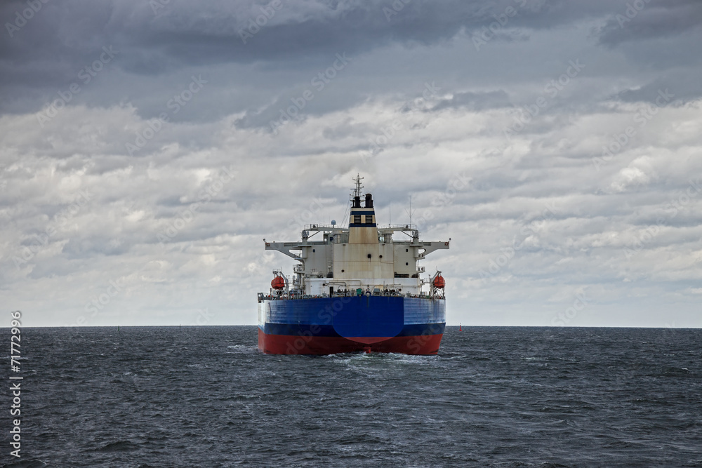 A large cargo ship at sea on a cloudy day. A large cargo ship at sea on a cloudy day.