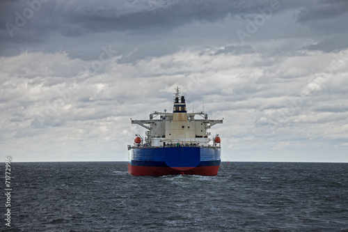 A large cargo ship at sea on a cloudy day.