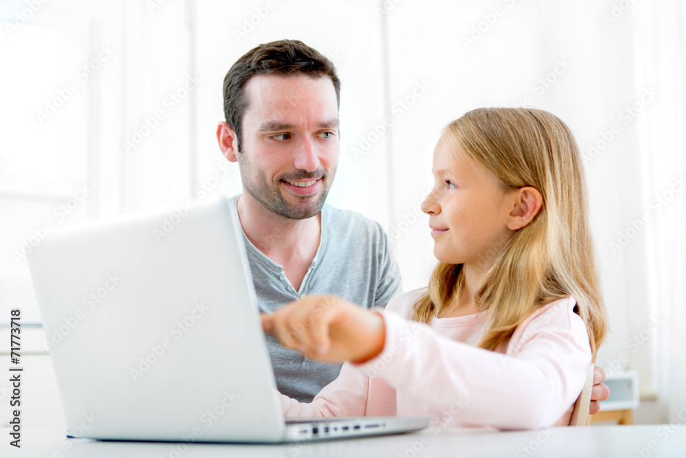 Father and his blond daughter using laptop