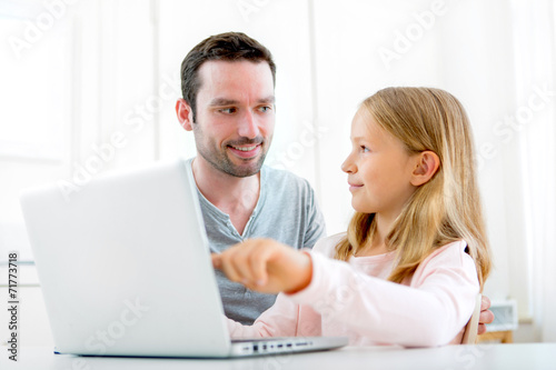 Father and his blond daughter using laptop
