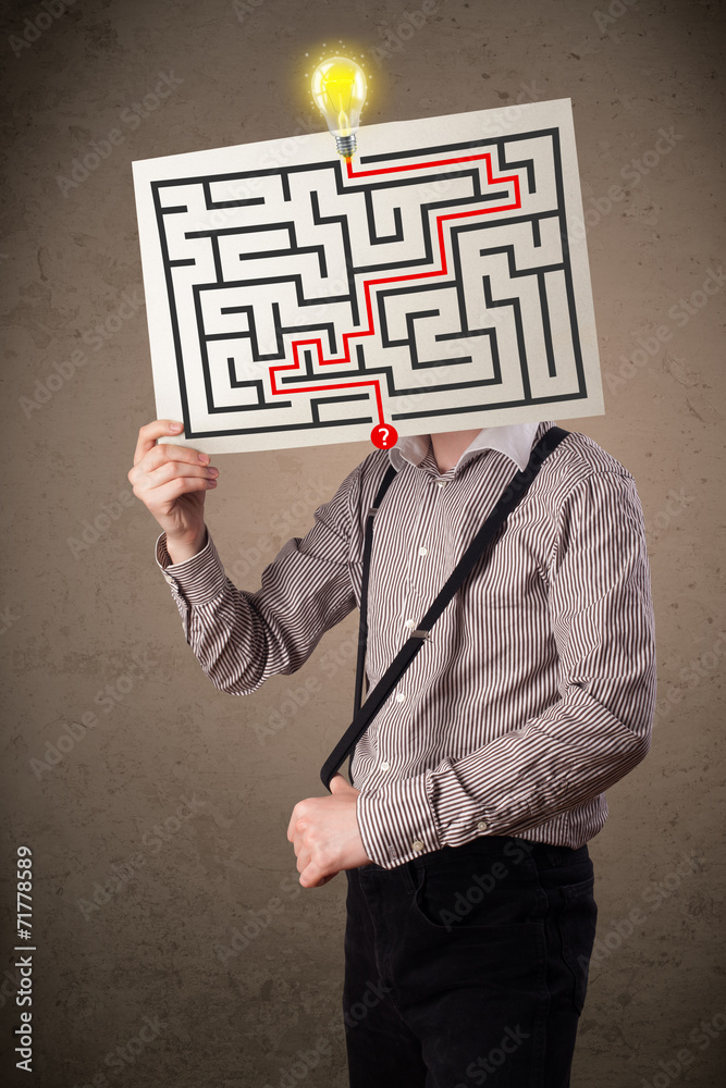 Businessman holding a paper with a labyrinth on it in front of h