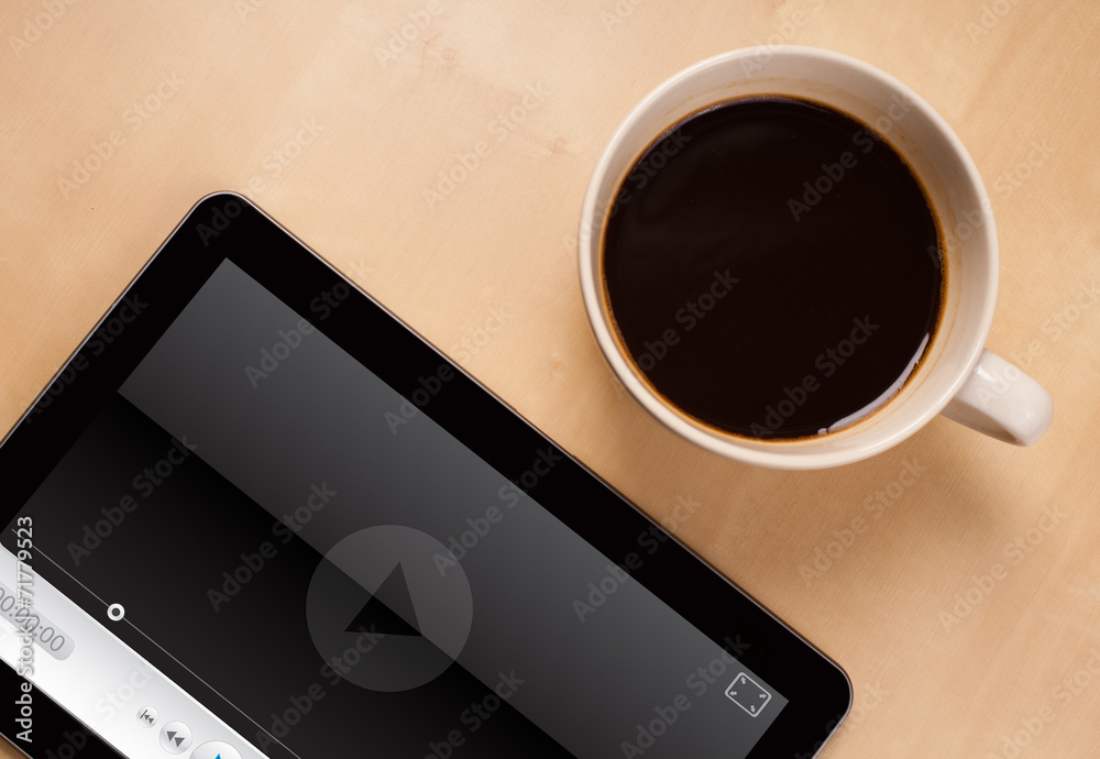 Tablet pc showing media player on screen with a cup of coffee on Tablet pc showing media player on screen with a cup of coffee on