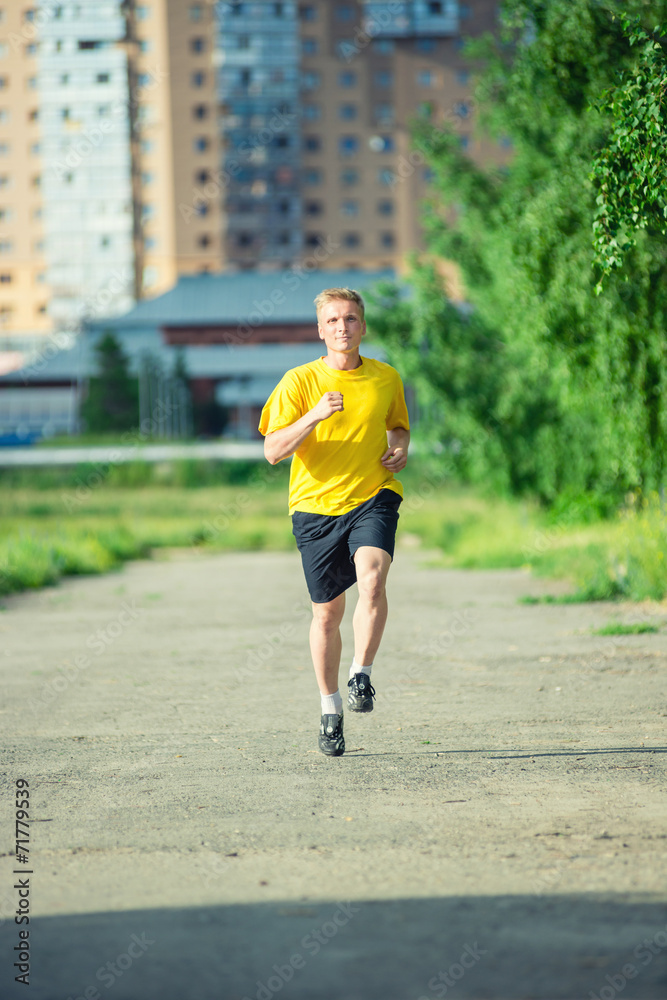 Sporty man jogging in city street park. Outdoor fitness.