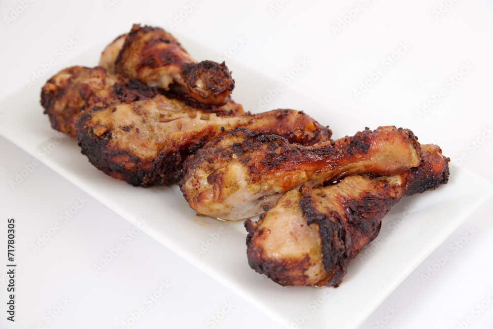Grilled chicken legs (drumsticks) on white plate