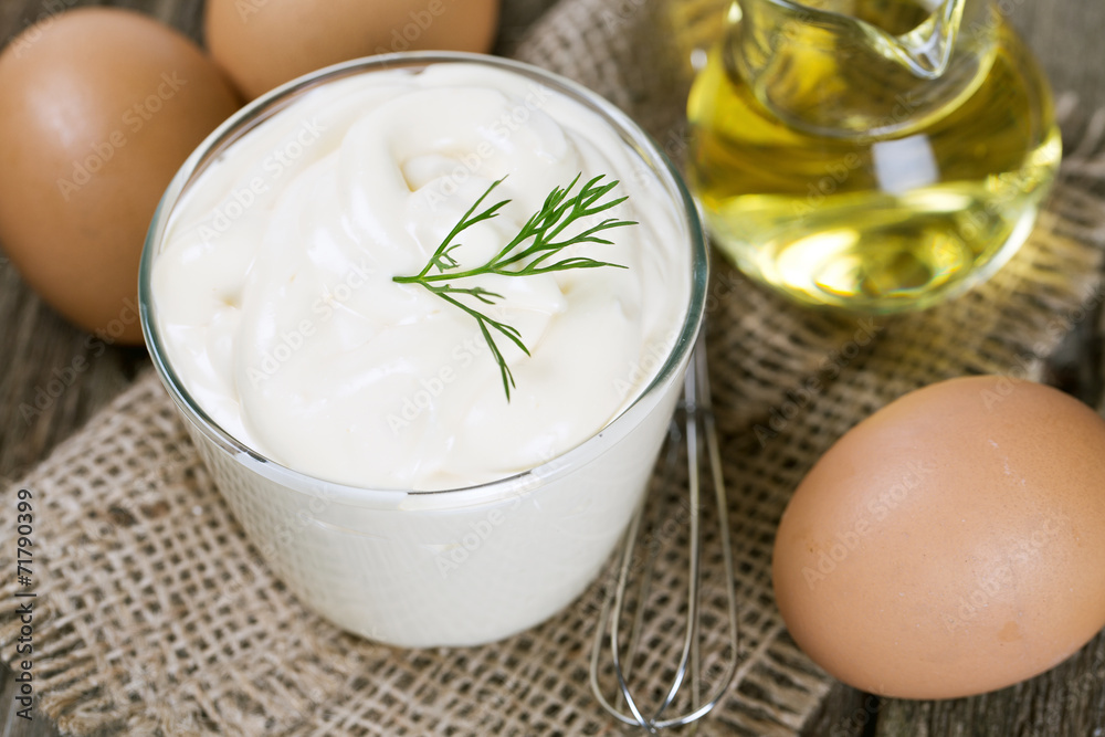 Mayonnaise in bowl with egg and olive oil on an old wooden table Mayonnaise in bowl with egg and olive oil on an old wooden table