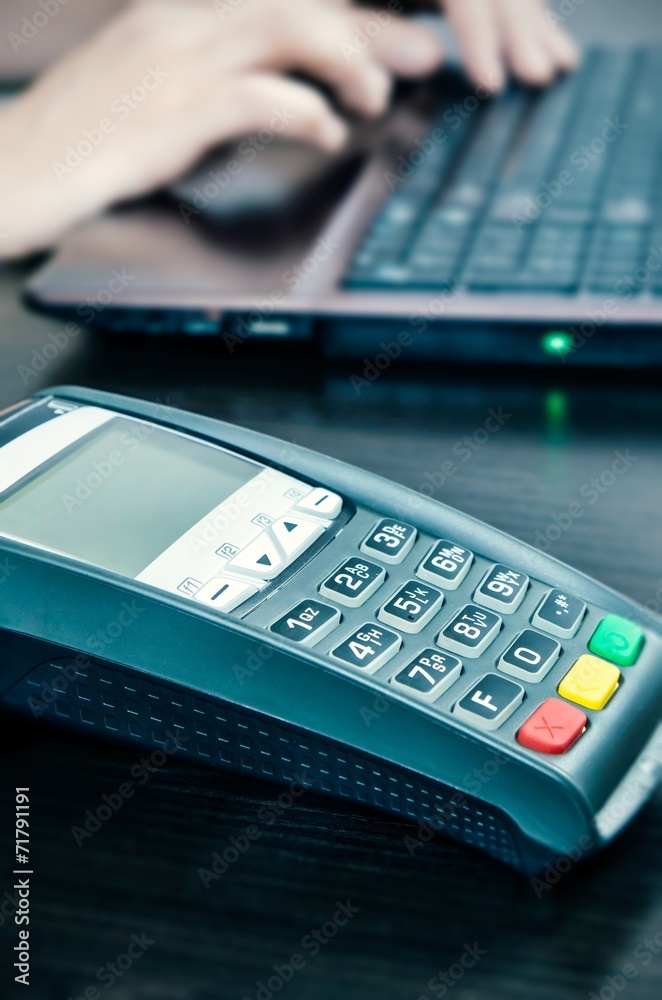 Payment terminal in the office. Man working with laptop in the b Payment terminal in the office. Man working with laptop in the b