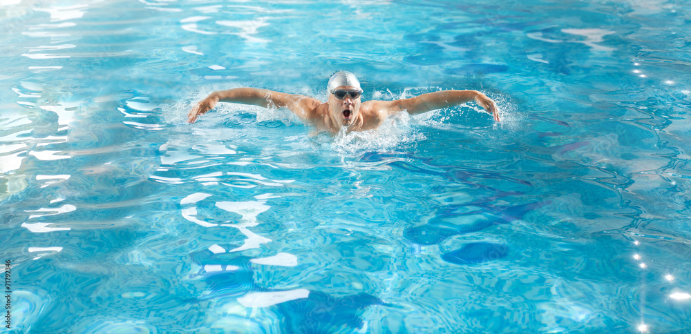 handsome athlete swimming in poll at butterfly style