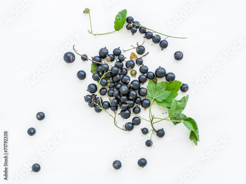 Black-currant berries and green leaves over a white wooden sufra