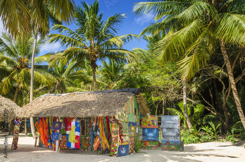 Fototapeta Beach with covered with a thatched roof hut with souvenirs