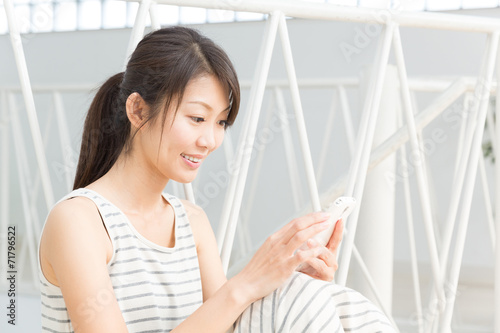 部屋でスマートフォンを見る女性