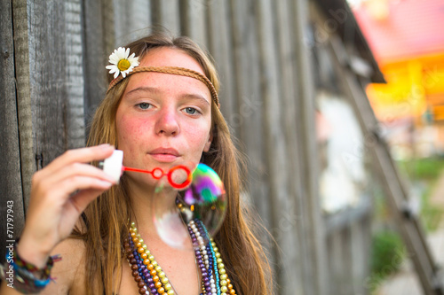 Hippie girl blows soap bubbles on a street .