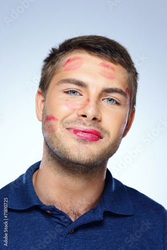 Portrait of young man with face full of lipstick marks of kisses photo