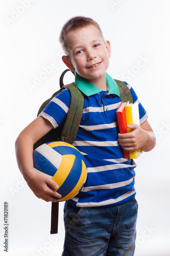 Happy schoolboy with backpack, ball and books 