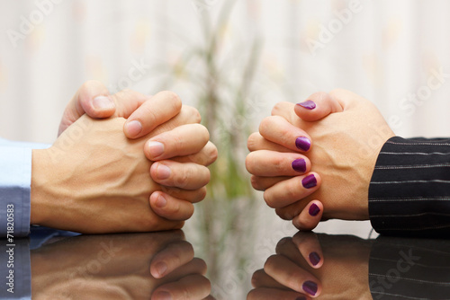 Man and woman sits at a desk with hands clasped. marital problem