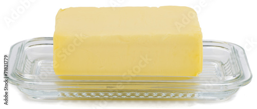 Piece of butter on glass butter dish over white background.