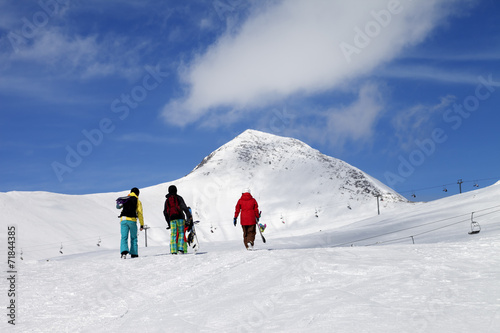 Three snowboarder on slope at sun nice day