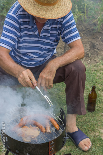 senior man with a straw hat at a barbecue