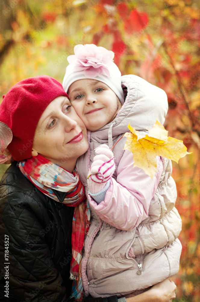 girl and mother are hiding behind a tree in the autumn park girl and mother are hiding behind a tree in the autumn park