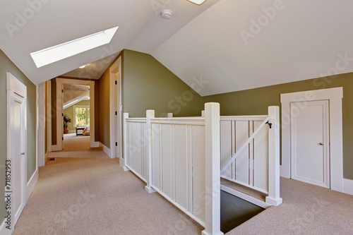 Green and white upstairs hallway with vaulted ceiling and skylig