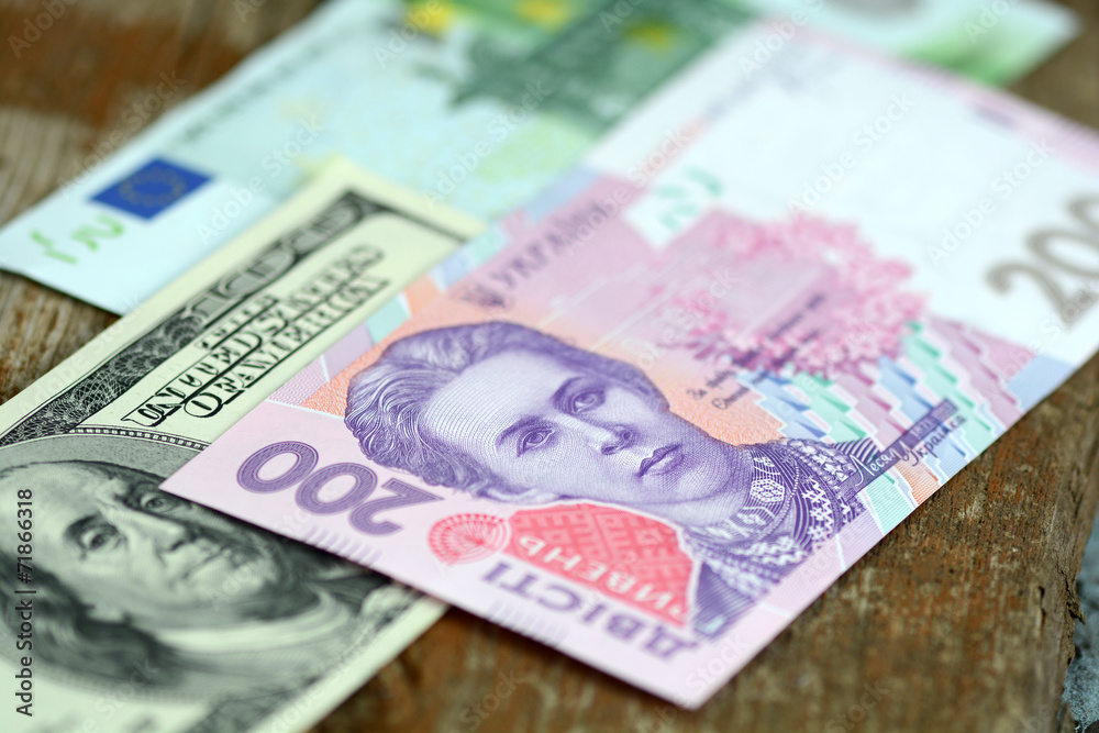 dollars euro and hryvnia banknotes on wooden background dollars euro and hryvnia banknotes on wooden background