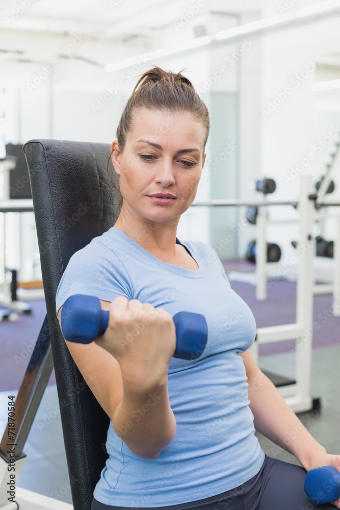 Fit brunette lifting blue dumbbells