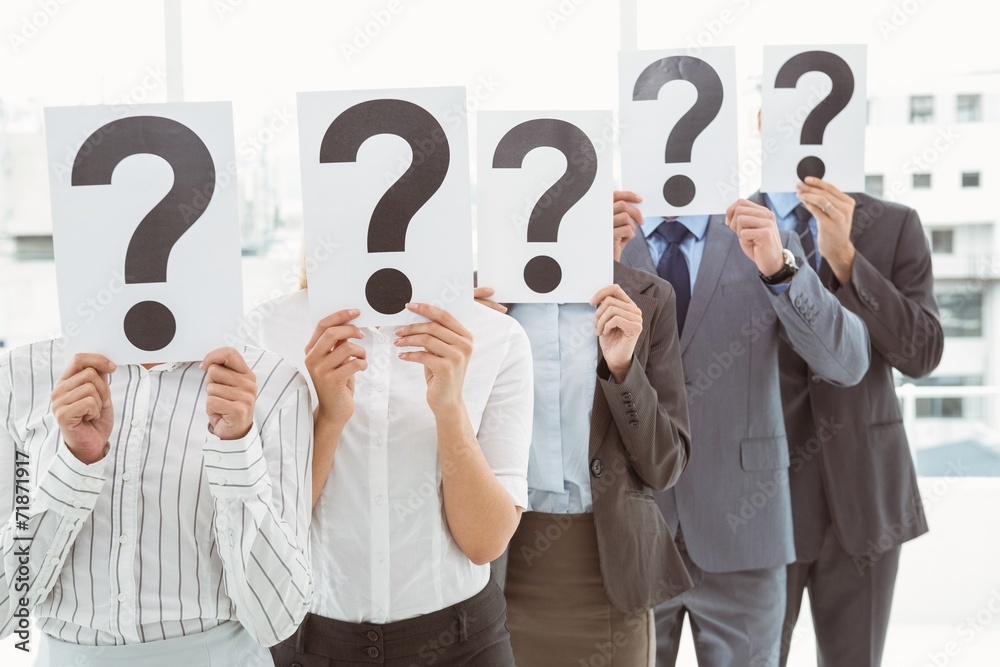 Business people holding question mark signs in office Business people holding question mark signs in office