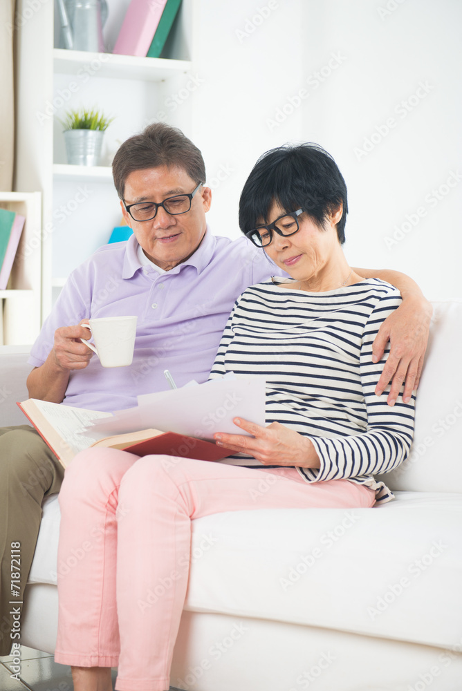 asian senior couple reading book and writing with coffee  or tea