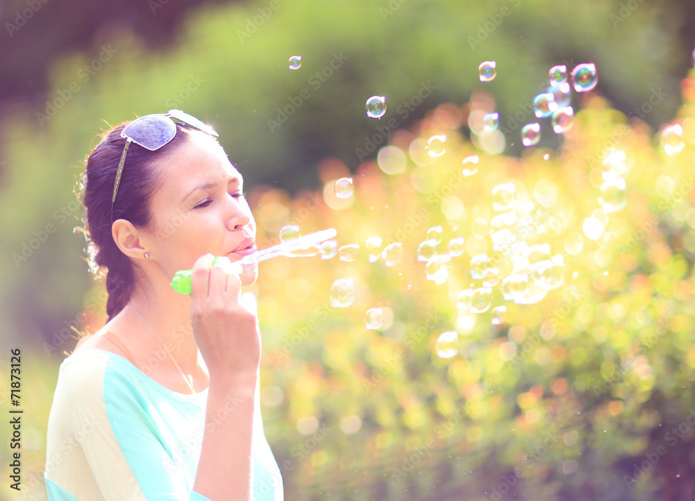 Gorgeous young brunette girl blowing soap bubbles