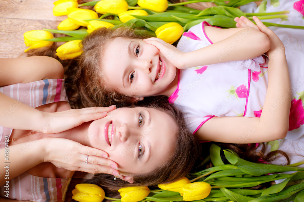 Fototapeta happy mother and daughter with yellow tulips at home