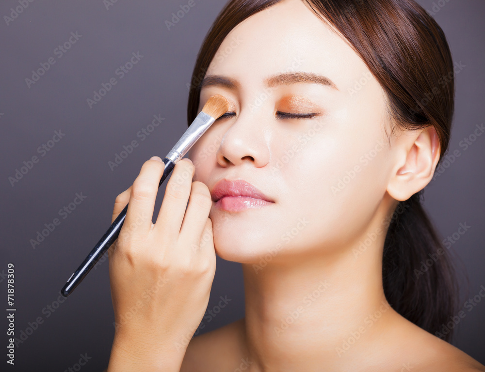 Make up artist applying  color eyeshadow on model's eye