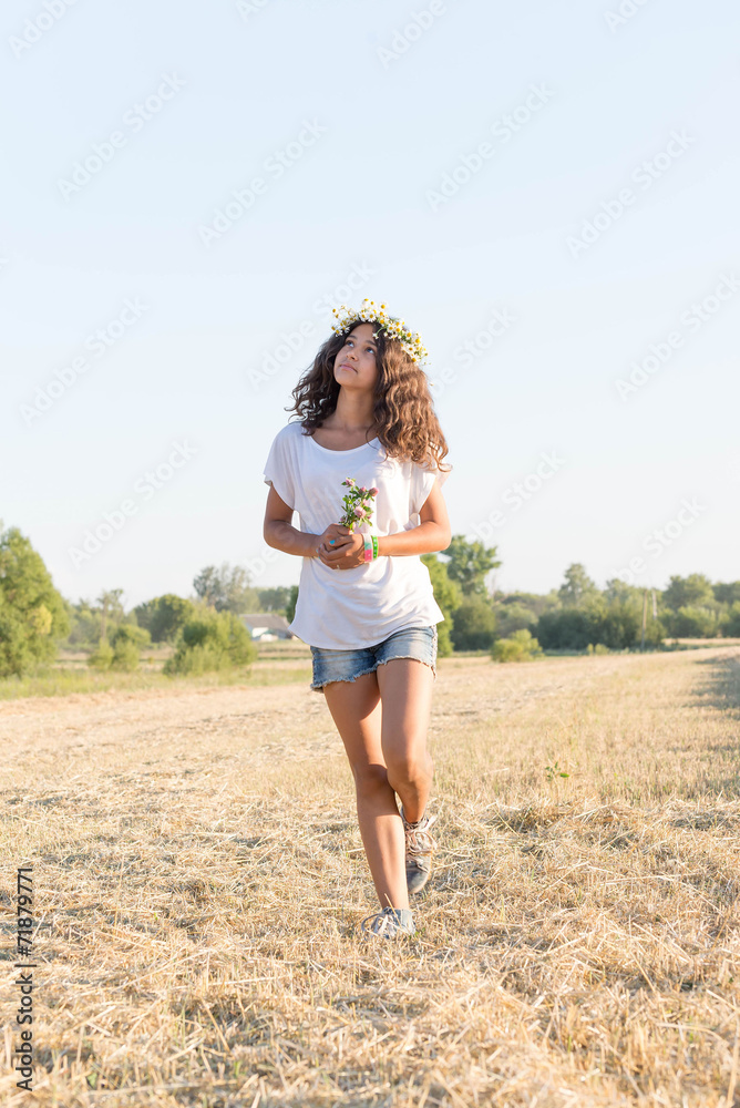 Teen girl in a wreath of daisies walketh in field Teen girl in a wreath of daisies walketh in field