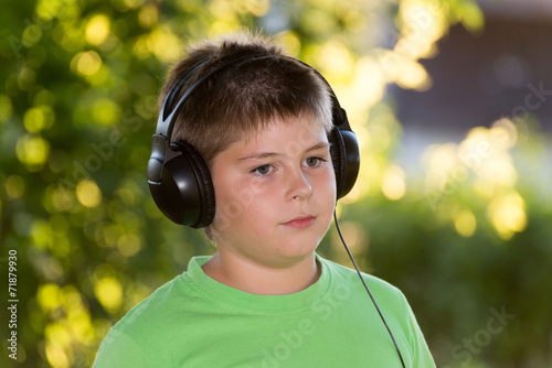 boy listening to music with headphones in  park