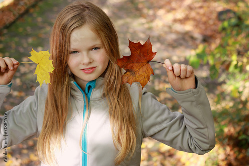 Beauty girl outdoors at autumn with two leafs