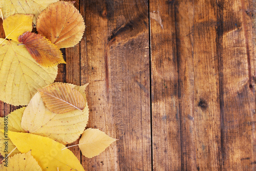 Yellow leaves on brown wooden background