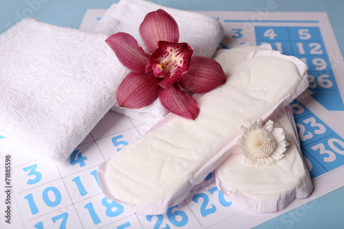 Sanitary pads and lilac orchid on blue calendar background