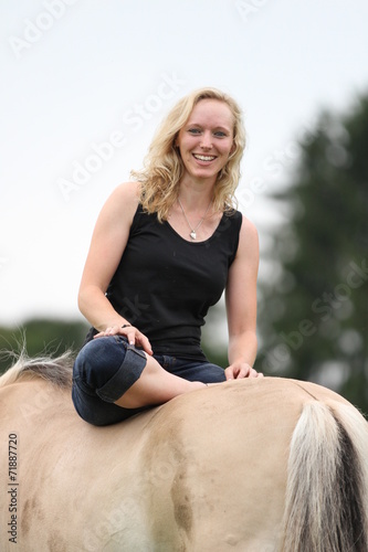 Frau sitzt lässig auf Fjordpferd photo