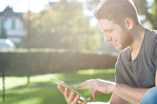 Junger Mann mit Tablet PC im Park