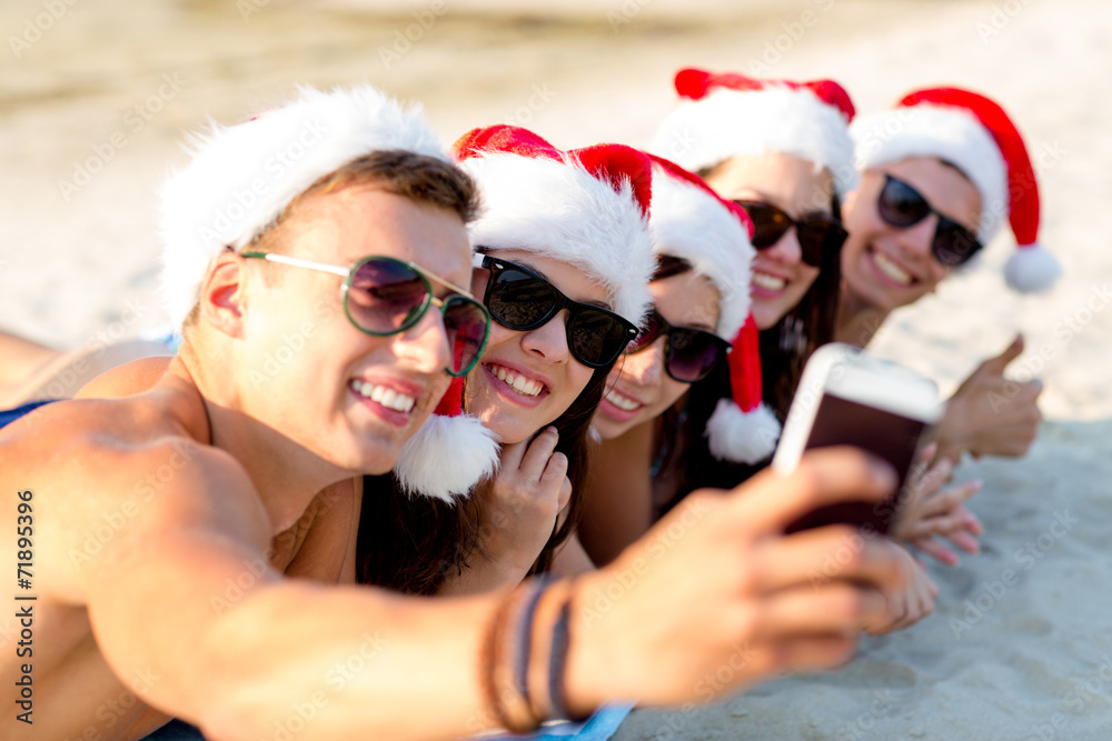Obraz premium group of friends in santa hats with smartphone