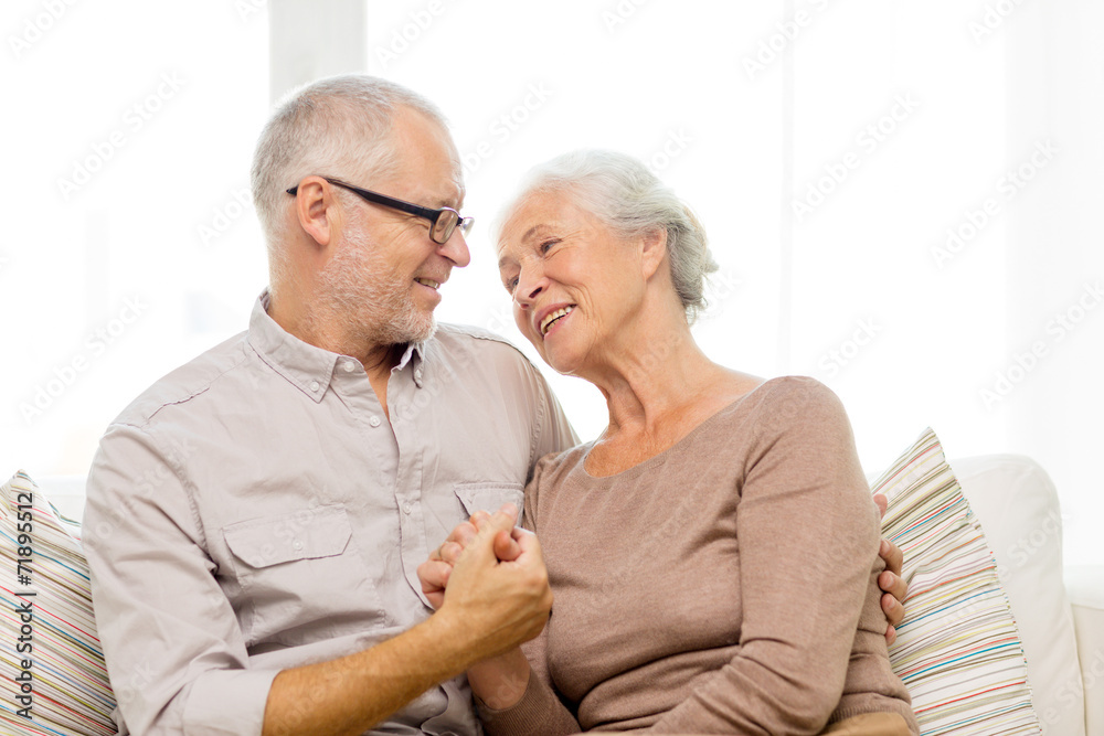 happy senior couple hugging on sofa at home