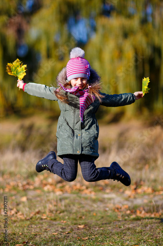 little girl jamping with autumn leaves photo